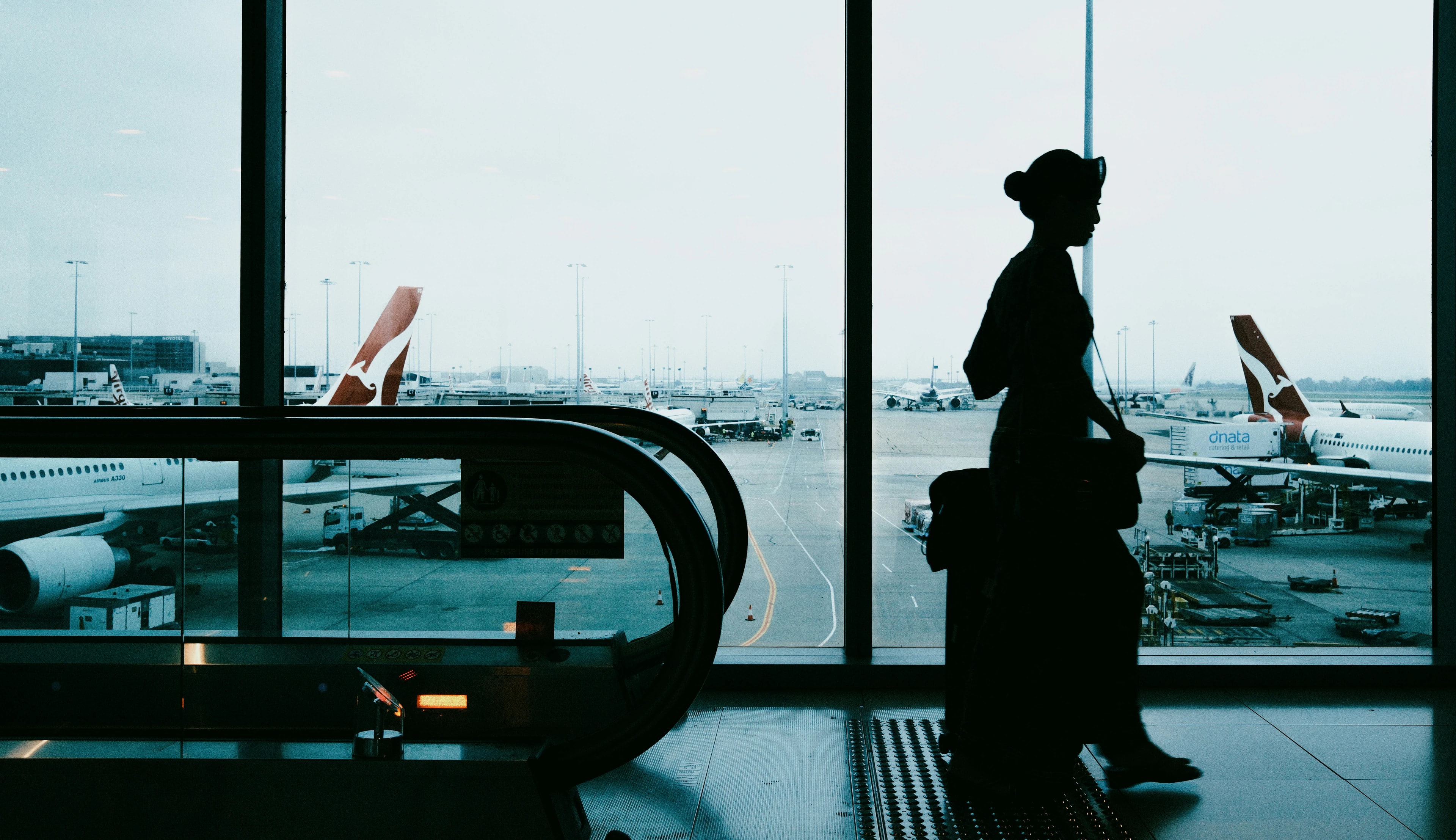 A student with a suitcase watching planes at the airport