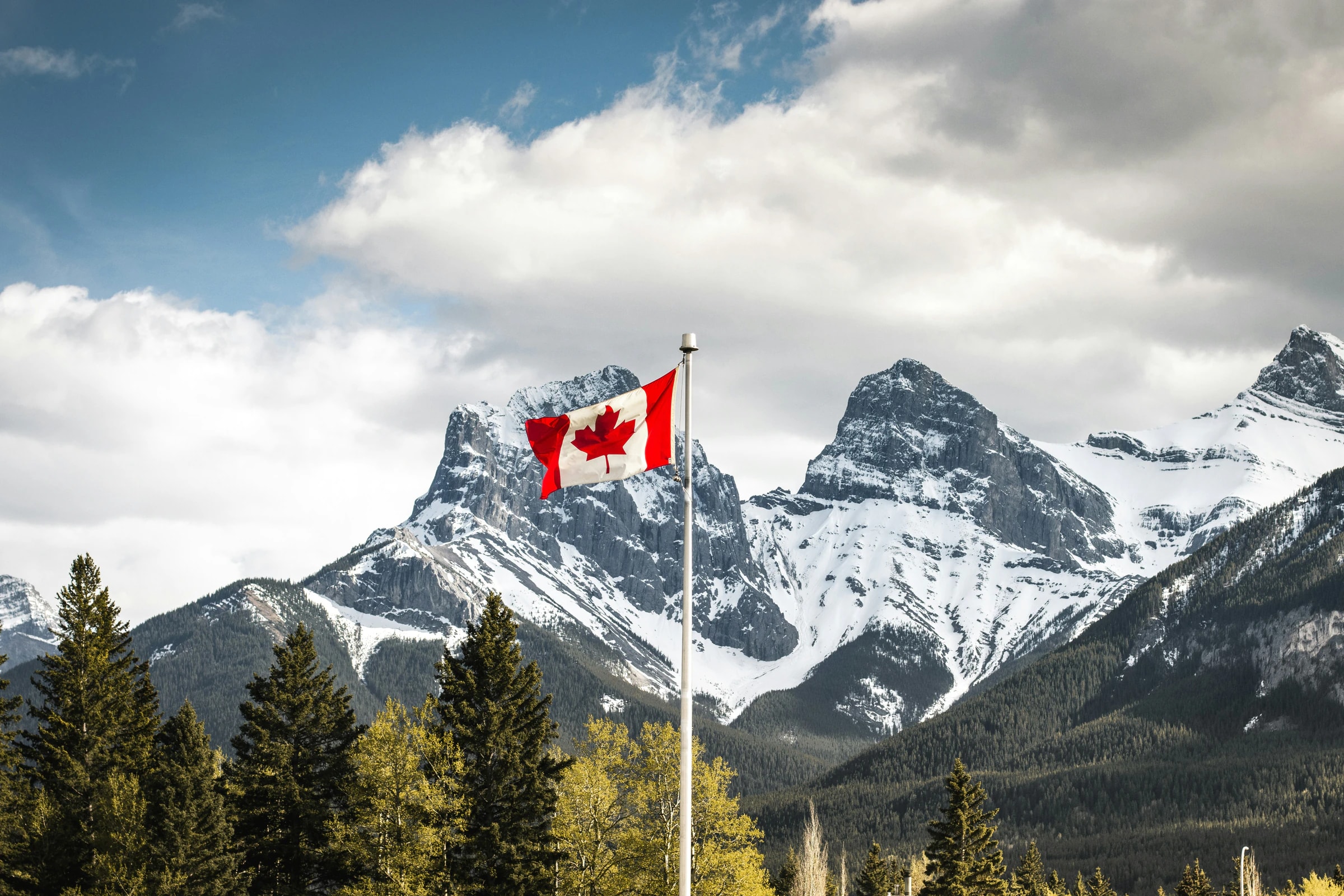 Canadian flag in front of snow-capped Rocky Mountains