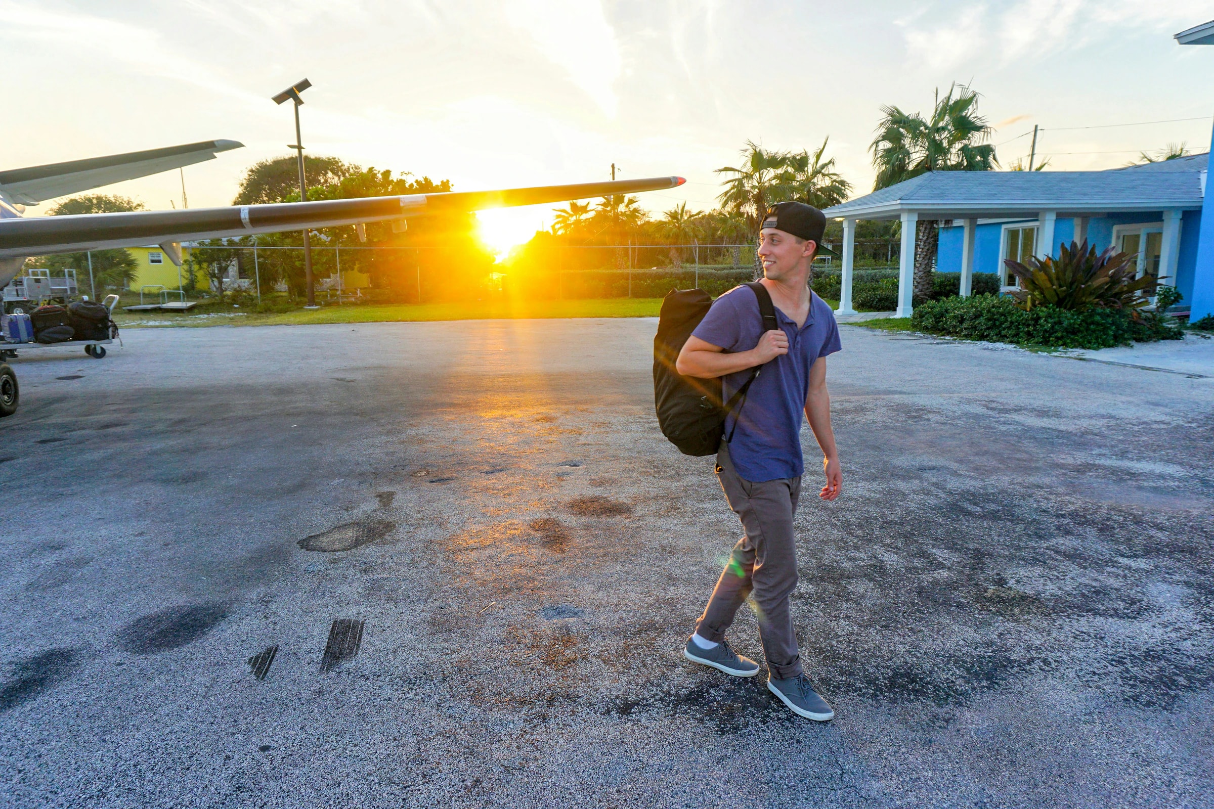 Student with a backpack walking past an aircraft at sunset